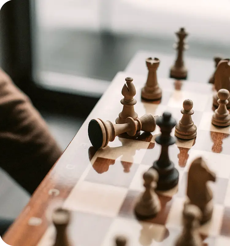 A person playing chess, some chess pieces have fallen on the board.