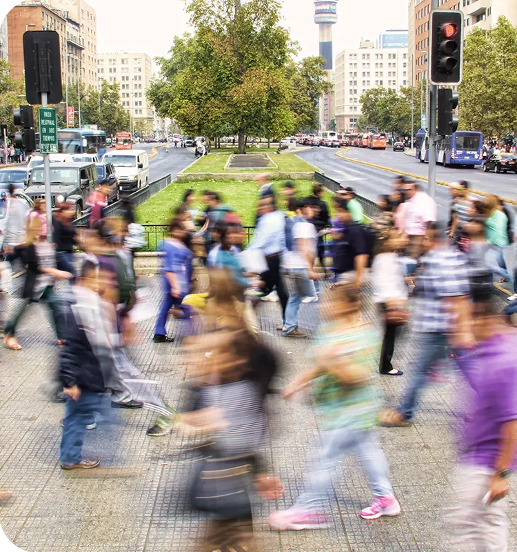 A lot of people crossing a crosswalk depicted in a motion blur, while cars are stopping.