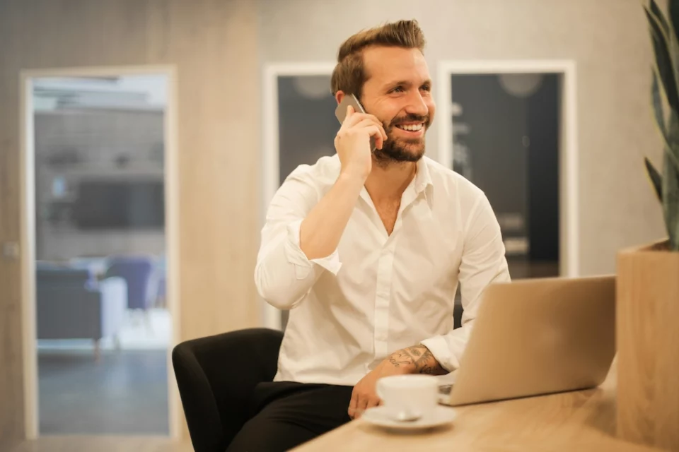 A man smilling and talking on the phone while sitting in an office