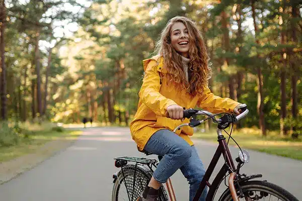 A woman smilling and riding a bicycle in a forest