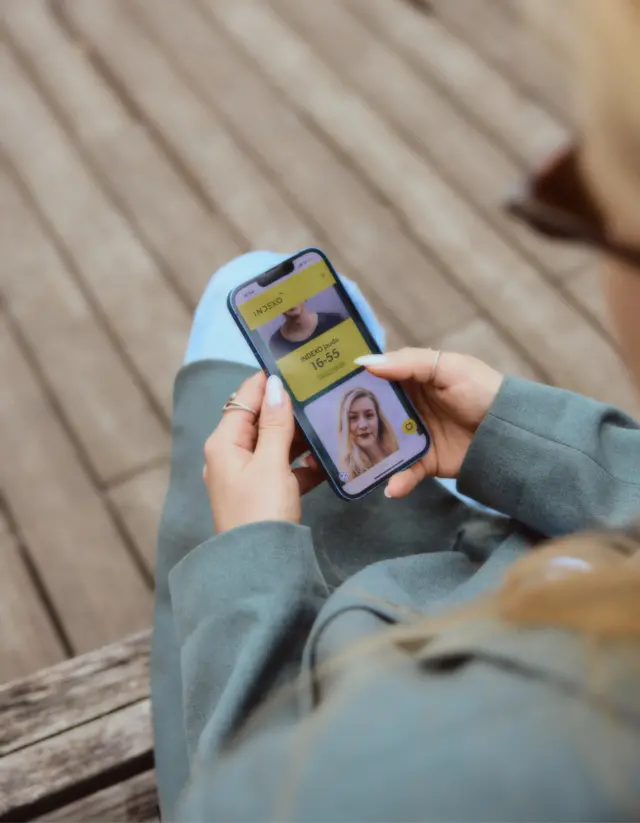 A person holds a smartphone with the INDEXO website open, where they can see pension plans.